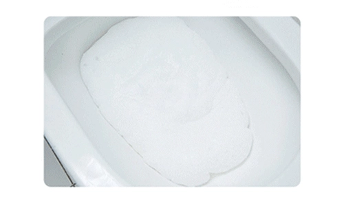 A toilet cleaner sheet dissolving in water, creating foam to break down stains and grime.